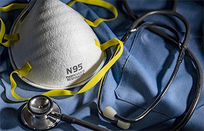 N95 mask and stethoscope laying on medical scrubs