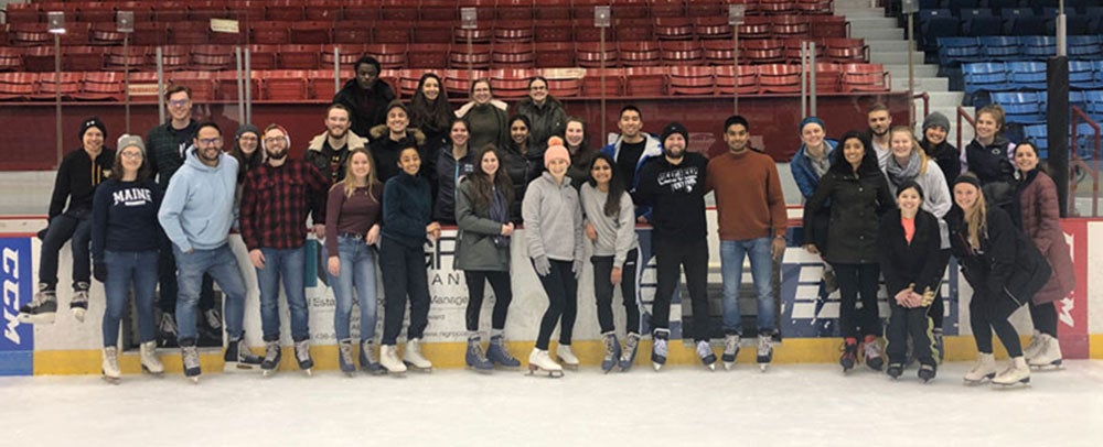 Group of grad students pose for a picture while ice skating