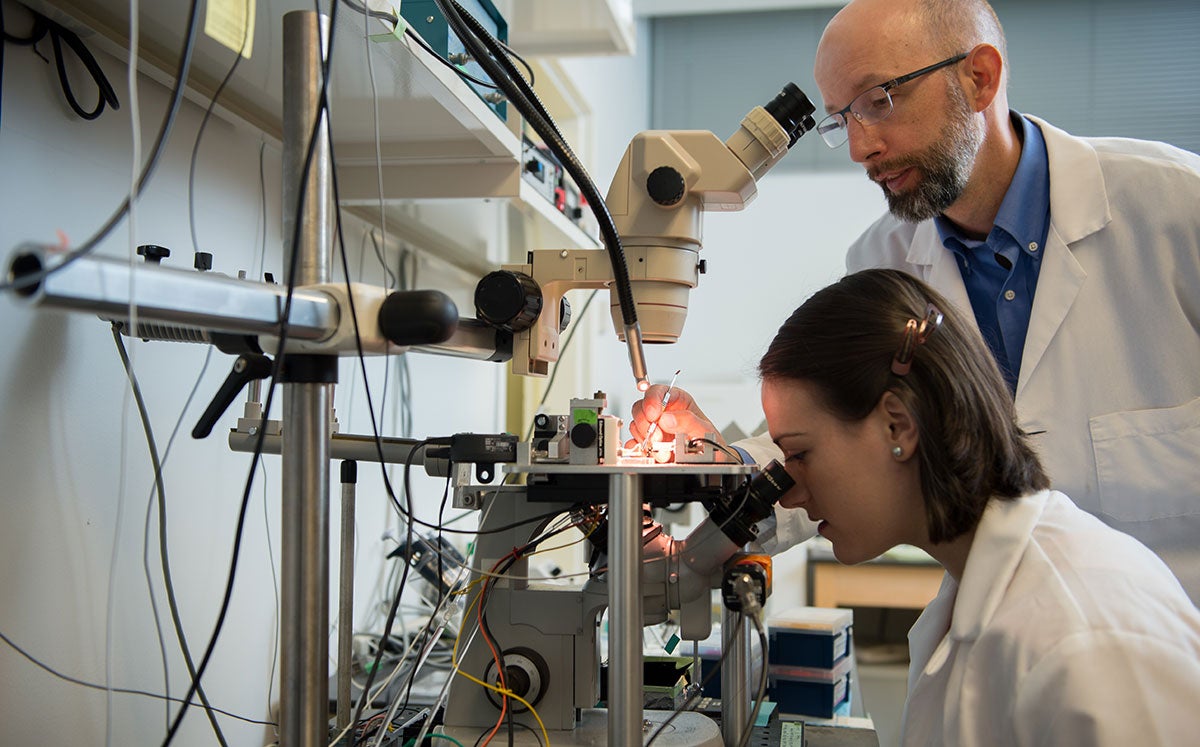 Professor working with a student using a microscope